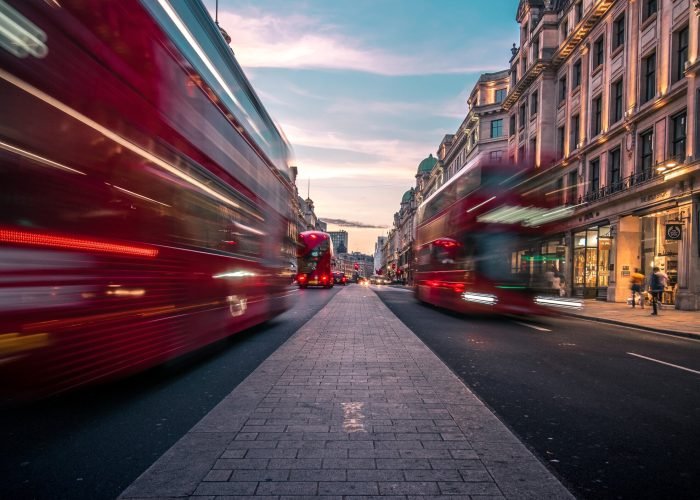 Dynamic scene of London buses in motion, illustrating the bustling energy of the city's transportation with a sense of speed and movement.