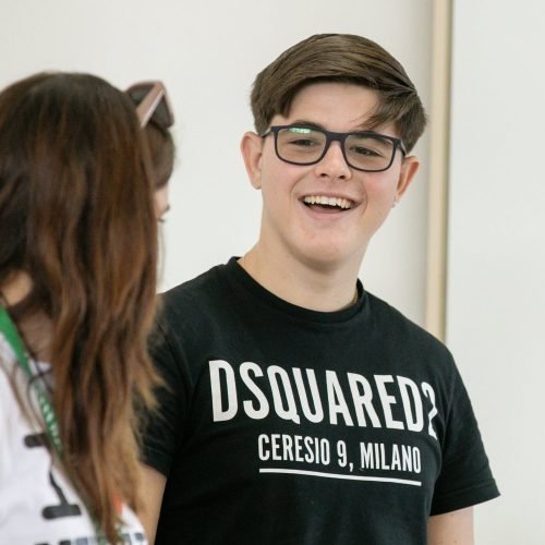 A happy student is talking with his classmate in Wimbledon School in London.